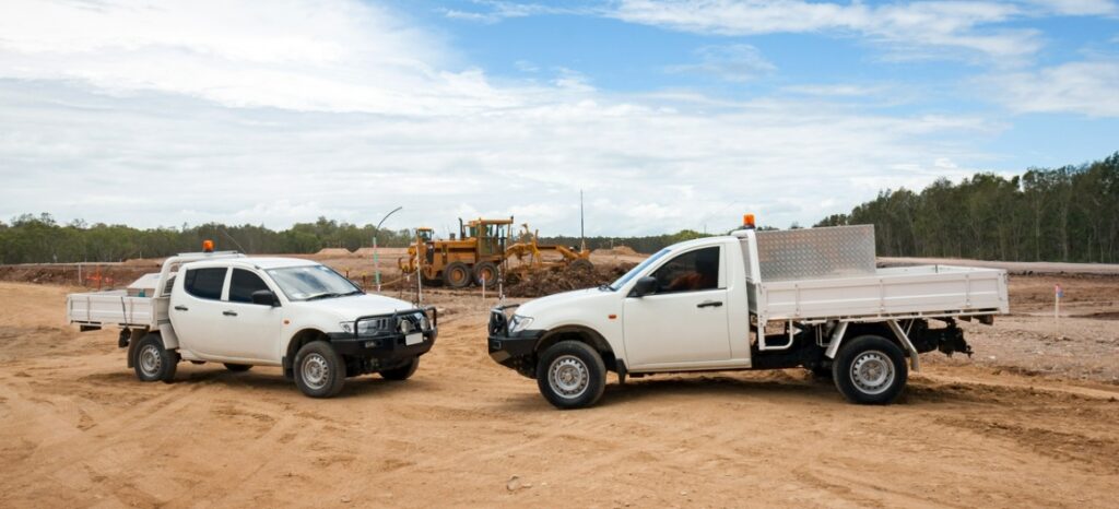 two customised utes on a construction site