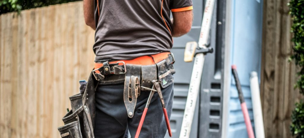 backside of construction worker with toolbelt in driveway