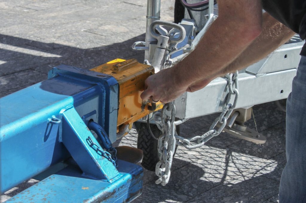 man hitching a trailer with a chain