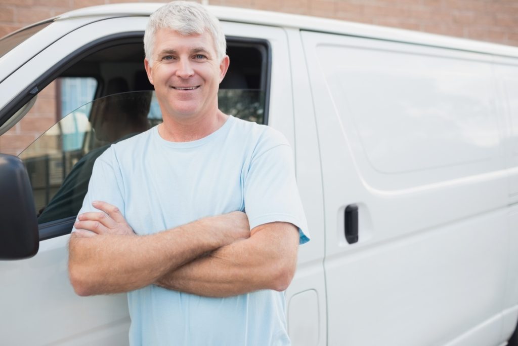 older man with arms crossed standing by commercial van