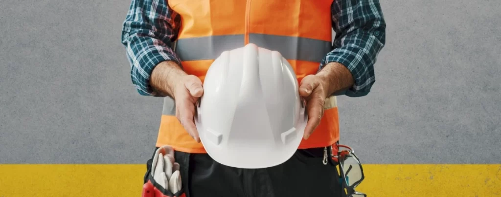 tradie wearing reflective vest and holding a hard hat