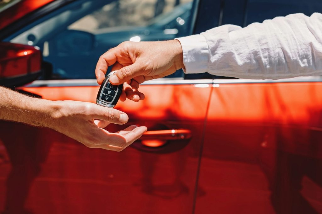 man handing another man keys to a new vehicle